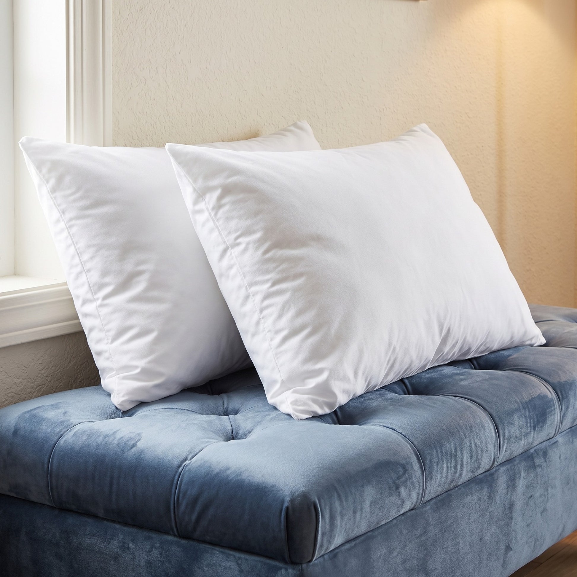BMNY 2-Pack Standard Pillow Set - two white standard pillows, 20 by 26 inches, on a blue tufted bench